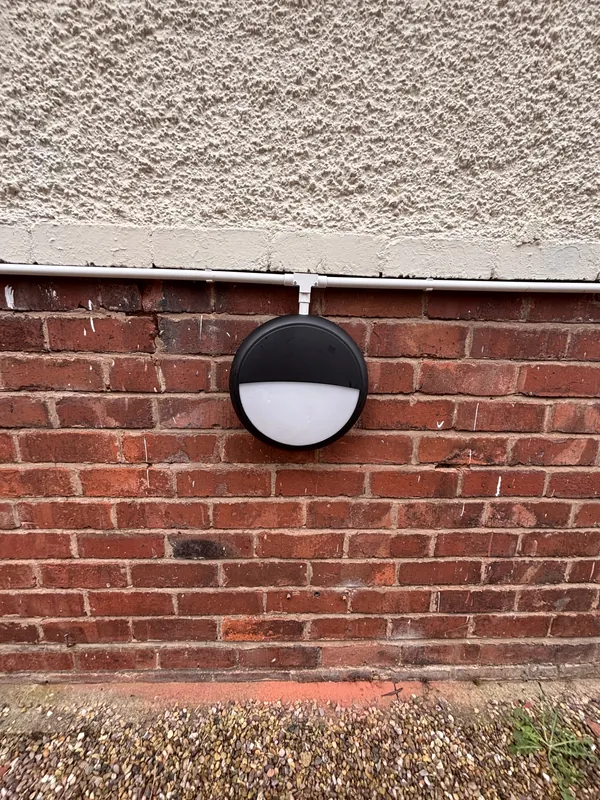 An outdoor bulkhead wall light fitted to brickwork