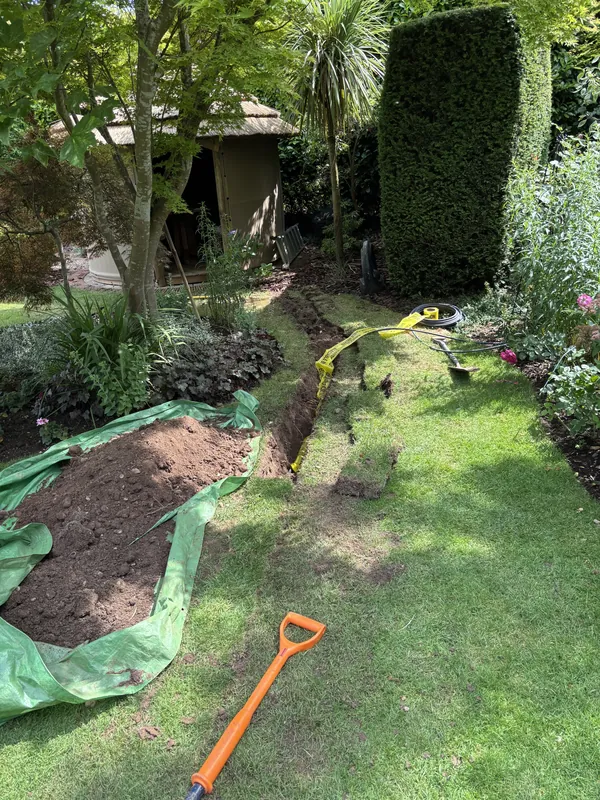 Armoured supply cable trenched across a garden to an outbuilding