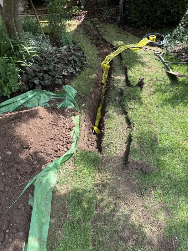 Underground armoured cable laid in a trench with warning tape above